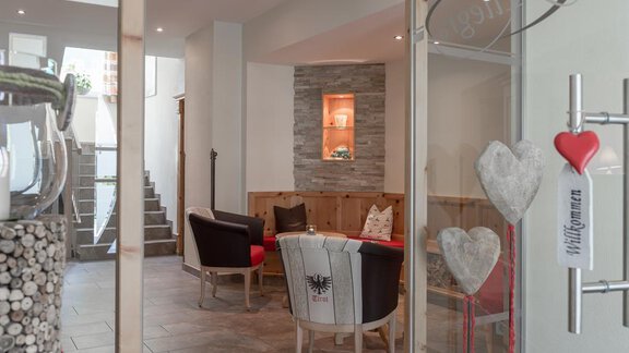 An inviting reception area with comfortable armchairs and stylish decorations. The room is bright and friendly, with a staircase in the background. - Residenz Allegra - Sölden | © Residenz Allegra Sölden