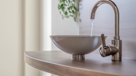 A modern sink with an elegant faucet. The water flow cascades into a simple, round basin. - Residenz Allegra - Sölden | © Residenz Allegra Sölden