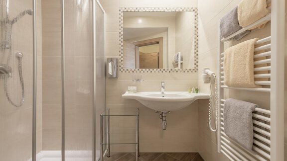 A modern bathroom with a walk-in shower and a large mirror. Towels are neatly placed on a towel rack. - Residenz Allegra - Sölden | © Residenz Allegra Sölden