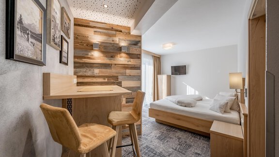 A modern room with a large bed and a cozy seating area. Wooden walls and tasteful decoration give the space an inviting atmosphere. - Residenz Allegra - Sölden