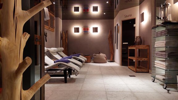 A quiet wellness area with loungers and soft lighting. Towels and various wooden elements can be seen on the wall. - Royal Appartement Sölden - Sölden