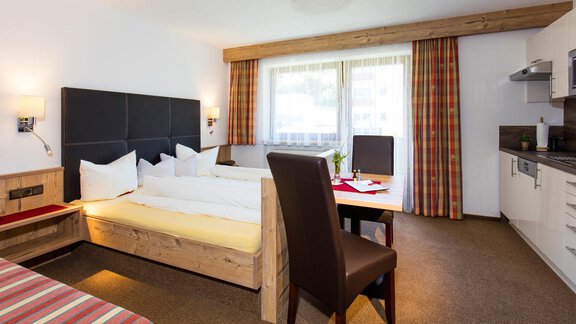 A modern hotel room with a double bed and a workspace. Large windows provide plenty of daylight and a relaxed atmosphere. - Sportpension Rubin - Sölden