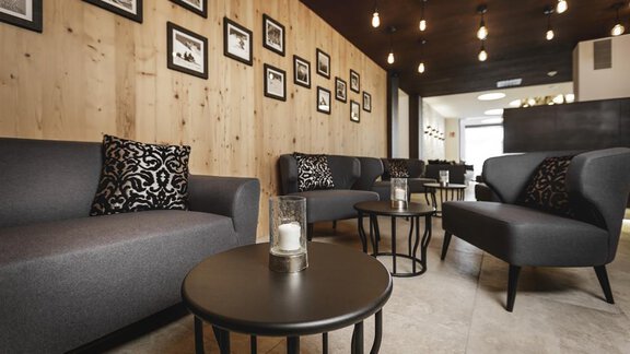 A modern living room with gray sofas and elegant cushions. Black and white pictures hang on the wall, and there are stylish tables with candles. - Valentin Design Apartment - Sölden
