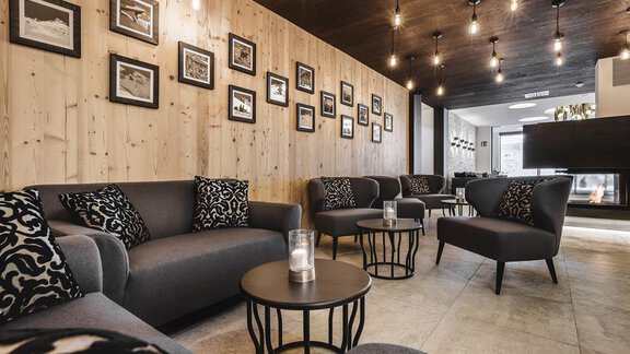 A modern lounge with stylish sofas and small tables. Black-and-white photographs hang on the walls in a cozy atmosphere. - Valentin Design Apartment - Sölden