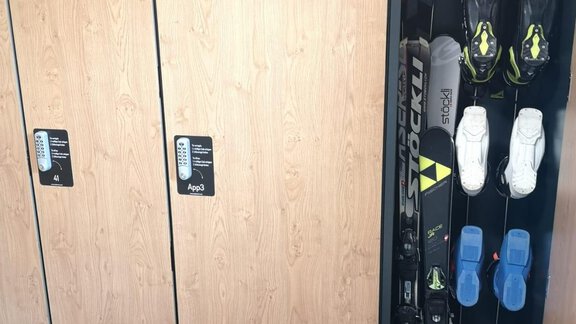 A ski locker with wooden fronts, where skis and accessories are stored. The skis are standing upright, and the ski boots are neatly stowed away. - Haus Christophorus - Obergurgl 