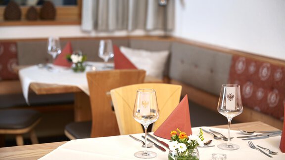 Ein einladendes Restaurant mit schön gedeckten Tischen. Die Dekoration umfasst Blumen und elegante Gläser. - Gasthof Walderhof - Ochsengarten