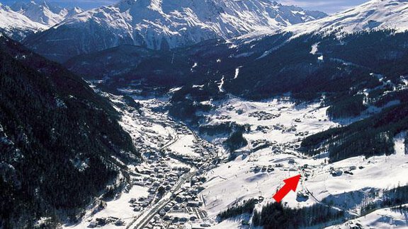 A picturesque winter landscape with snow-covered mountains and a small village in the valley. The clear, blue sky creates a calm atmosphere. - Apart Hotel Garni Wieser - Sölden