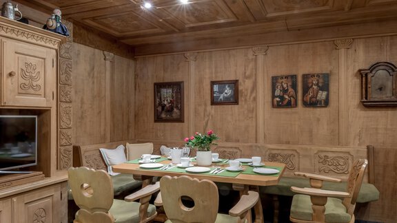 A cozy dining room with wooden paneled walls and a large dining table. The table is set and there are pictures hanging on the wall. - Apart Hotel Garni Wieser - Sölden