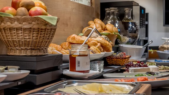A lavish breakfast buffet with fresh rolls, cold cuts, and a selection of fruit. There is also honey and various side dishes in attractive bowls. - Apart Hotel Garni Wieser - Sölden