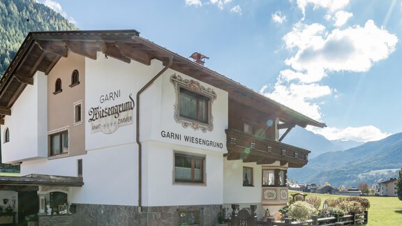 A traditional guesthouse named "Garni Weisengrund" in a picturesque mountain landscape. The facade displays a charming alpine style, and the surroundings are green and inviting. - Apart Wiesengrund - Sölden