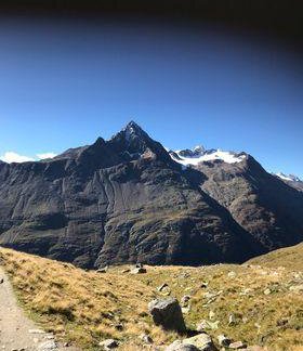An impressive mountain landscape with a distinctive peak and clear blue sky. In the foreground, a natural green meadow is visible. - Gästehaus Europa - Sölden