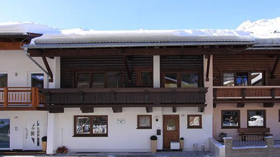 A traditional house in the mountains with wooden cladding and a snow-covered roof. The surroundings are clear and sunny. - Haus Ingrid - Sölden