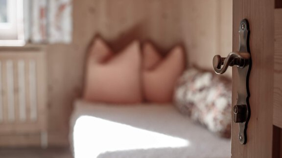 A cozy room with wood paneling and a daybed. On the bed, there are cushioned pillows in soft colors. - Haus Ingrid - Sölden