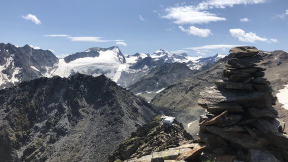 A stunning mountain view with snow-capped peaks and a rocky viewpoint. The sky is clear and blue. - Hotel Sportpension Carinthia - Sölden