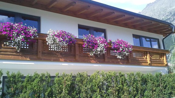 Ein schönes Haus mit einem Holzbalustrade-Balkon. Der Balkon ist üppig mit bunten Blumenpflanzen dekoriert. - La Luna - Sölden