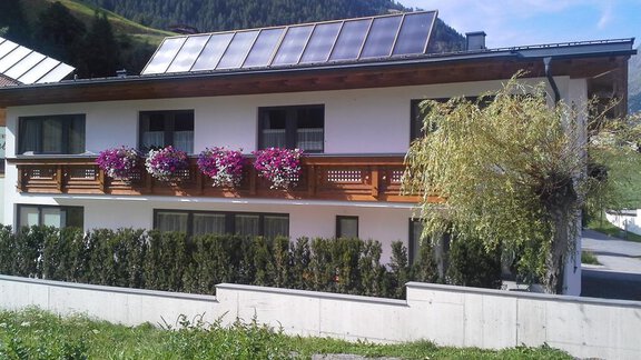 Ein schönes Haus mit einem hügeligen Hintergrund. Der Balkon ist mit bunten Blumen verziert und es gibt Solarpanele auf dem Dach. - La Luna - Sölden