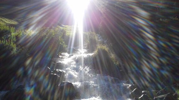 Ein schöner Wasserfall, der in der Sonne glitzert. Helle Strahlen brechen durch die Bäume im Hintergrund. - La Luna - Sölden