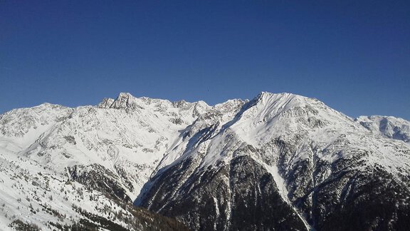 Eine verschneite Berglandschaft unter einem strahlend blauen Himmel. Die majestätischen Gipfel sind von Schnee bedeckt und strahlen Ruhe aus. - La Luna - Sölden