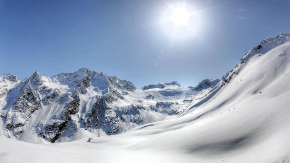 A breathtaking mountain panorama with snow-capped peaks and a radiant blue sky. The sun shines brightly over the snowy landscape. - Landhaus Falkner - Sölden