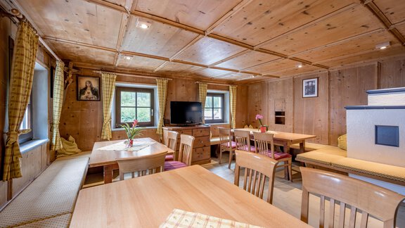 A cozy room with wooden walls and large windows. There are several tables and chairs as well as a comfortable seating area. - Landhaus Peater's Hoamat - Sölden