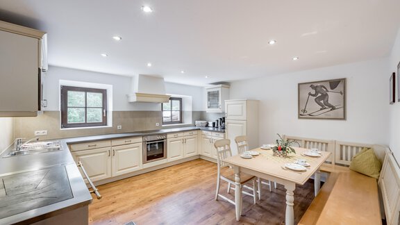 A modern kitchen with bright cabinets and a large table. The space is designed to be friendly and inviting. - Landhaus Peater's Hoamat - Sölden