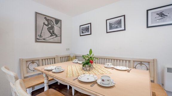 A cozy dining area with a large table and chairs. Black and white pictures featuring ski motifs hang on the walls. - Landhaus Peater's Hoamat - Sölden