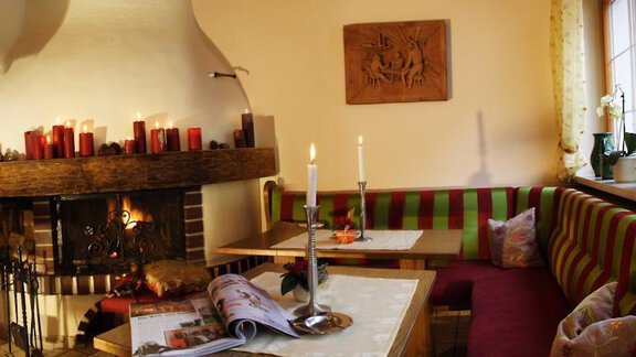 A cozy room with a fireplace, featuring candles and decorative elements. The seating area is comfortable and inviting, perfect for relaxing evenings. - Pension Sportalm - Sölden