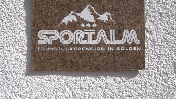 A sign with the inscription "Sportalm" and the addition "Breakfast guesthouse in Sölden". In the background, stylized mountain graphics are visible. - Pension Sportalm - Sölden