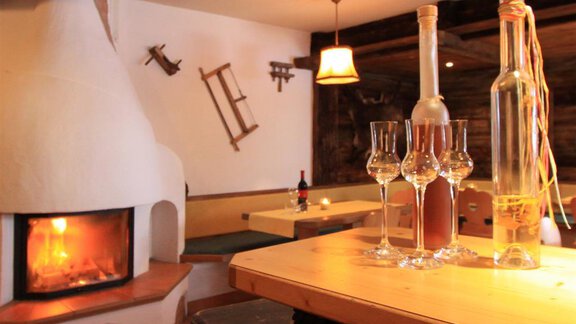 A cozy room with a fireplace and a wood stove. Glasses and bottles are on the table, creating an inviting atmosphere. - Toni's Ferienheim - Sölden