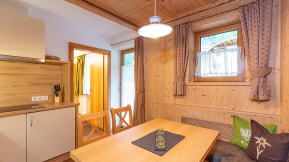 A cozy kitchen with wooden furniture and a dining table. The room has large windows that let in plenty of light. - Vizensn Living - Sölden