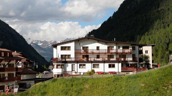 A beautiful building in the mountains with balconies and surrounded by a green meadow. In the background, tall mountains and a cloudy sky can be seen. - Gästehaus Soldanella - Vent