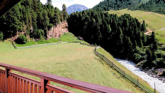 A picturesque landscape with green meadows and tall trees. In the background, there are mountains and a flowing brook. - Gästehaus Soldanella - Vent