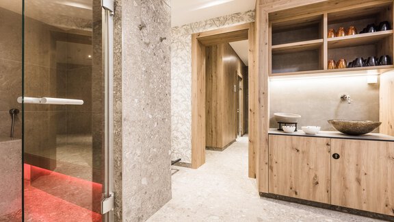 A modern bathroom with wooden shelves and elegant lighting. The shower is made of glass and has a minimalist style. - Andre Arnold - Boutique Hotel - Sölden