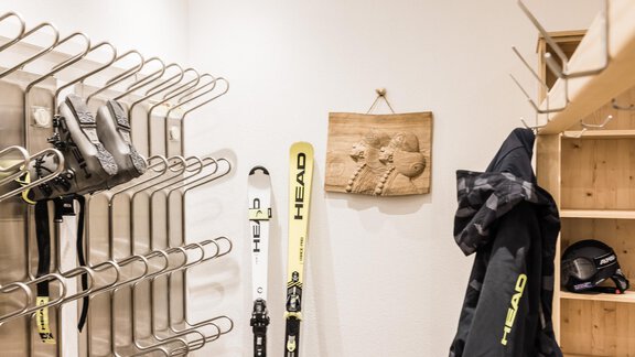 A ski room with skis, ski boots, and a jacket. The walls are bright and the furnishings are functional. - Andre Arnold - Boutique Hotel - Sölden