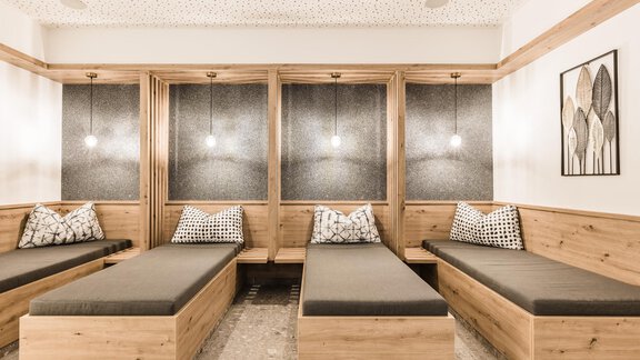 A cozy relaxation room with wooden paneling and comfortable loungers. Soft lighting creates a serene atmosphere. - Andre Arnold - Boutique Hotel - Sölden