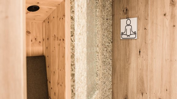 A relaxing space with wooden paneling and meditation symbolism. A cozy seating area invites you to linger. - Andre Arnold - Boutique Hotel - Sölden