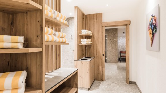 A modern room with wooden shelves holding striped towels. The room has a bright, welcoming atmosphere. - Andre Arnold - Boutique Hotel - Sölden