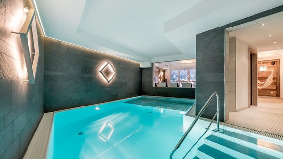 An elegant indoor pool with clear blue water and modern design. Soft lighting creates a relaxing atmosphere. - Appartementhaus A CASA "Kristall" - Sölden