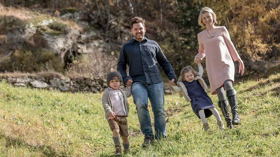 A family with two small children happily walks on a meadow. The surroundings display autumn colors and a natural landscape. - CORSO living Aparthotel - Sölden