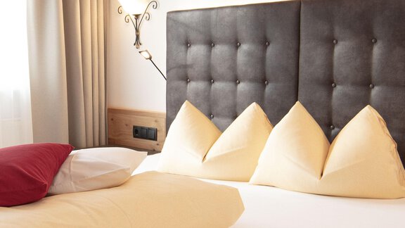 A cozy bedroom with a large bed and carefully folded pillows. The walls are bright and the decor is modern. - Haus Gondelblick - Sölden | © Falkner Georg