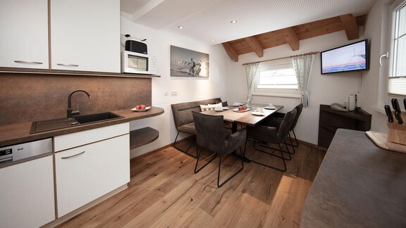 A modern kitchen with a large dining table and cozy seating. The decor is bright and inviting. - Haus Gondelblick - Sölden | © Falkner Georg