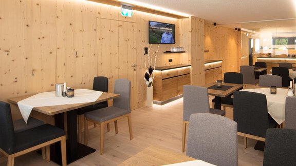 A modern restaurant with wooden decor and elegant tables. The furnishings are warm and inviting, perfect for social meals. - Haus Gondelblick - Sölden | © Falkner Georg