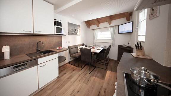A modern kitchen with wooden floors and elegant furniture. The dining area is well-lit and inviting. - Haus Gondelblick - Sölden | © Falkner Georg