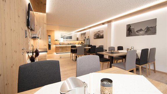 A modern dining room with a large table and comfortable chairs. The walls are in warm wood tones, and the atmosphere is inviting and cozy. - Haus Gondelblick - Sölden | © Falkner Georg