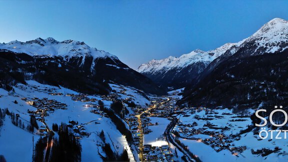 An impressive winter landscape in Sölden with snow-covered mountains and a clear sky. The town is brightly lit and surrounded by picturesque Alps. - Haus Gondelblick - Sölden | © Falkner Georg