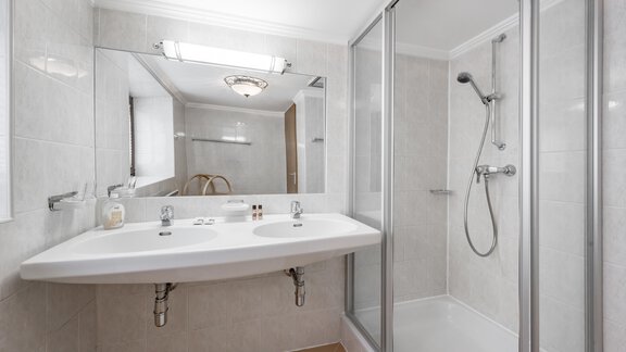 A modern bathroom with a shower and a double washbasin. Bright tiles and a large mirror create a pleasant atmosphere. - Landhaus Peater's Hoamat - Sölden