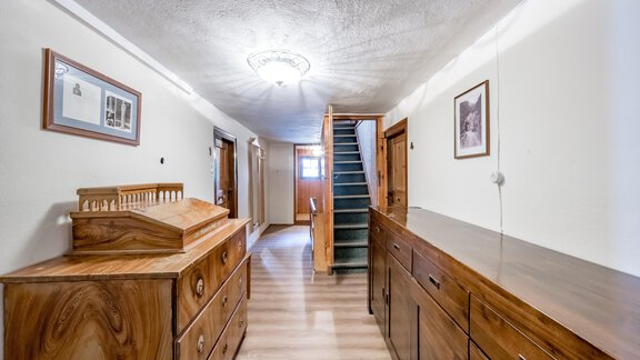 A bright hallway with wooden furniture and a staircase. Pictures hang on the walls and there is a beautiful ceiling light. - Landhaus Peater's Hoamat - Sölden