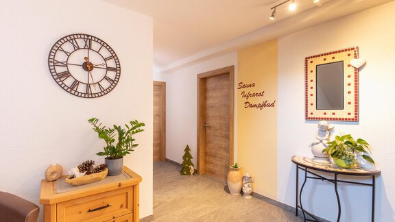 An inviting hallway with bright walls and modern wall decor.  
Plants and decorative furniture create a cozy atmosphere. - Sportpension Rubin - Sölden