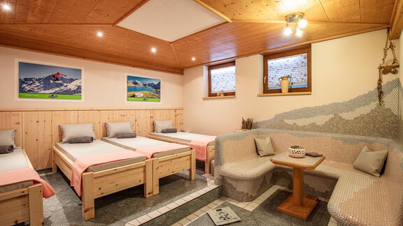 A cozy room with wooden beds and a seating area. Pictures of mountains hang on the walls, and large windows provide ample light. - Sportpension Rubin - Sölden