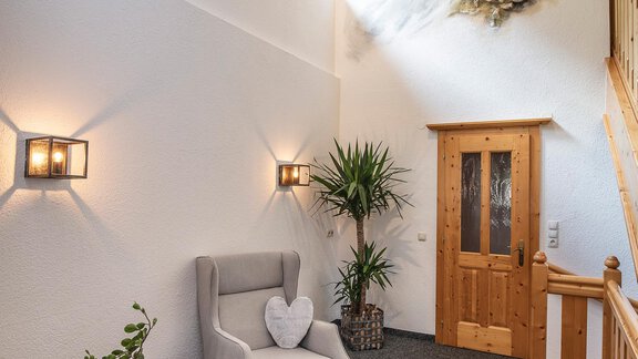 A cozy entrance area with a comfortable armchair and a beautiful plant. On the wall, there is a large painting of a mountain landscape. - Vizensn Living - Sölden